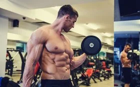Ein junger Bodybuilder mit freiem, muskulösen Oberkörper macht einen Bizepscurl mit einer Kurzhantel.