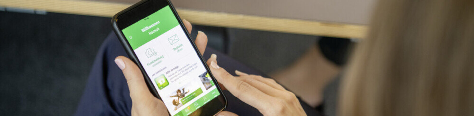 Eine Frau hält ihr Smartphone in der Hand. Mit dem Einmal-PIN kann sie Daten online an ihre Krankenkasse übermitteln.