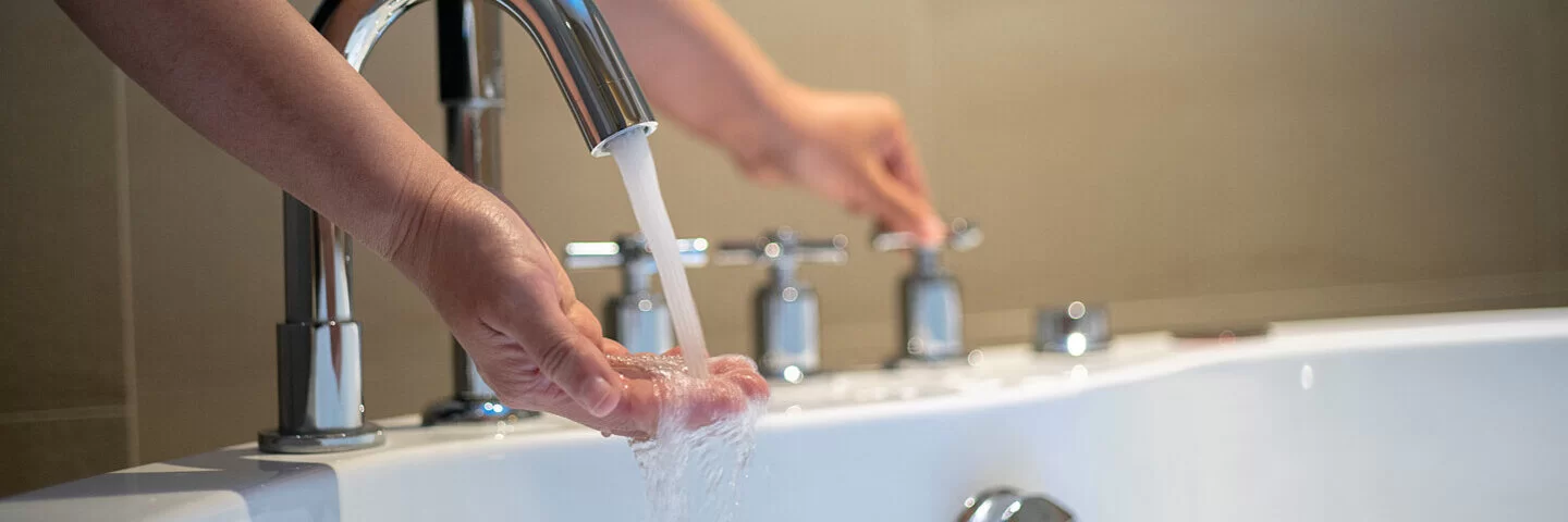 Eine Person füllt Wasser in eine Badewanne für ein Sitzbad ein.