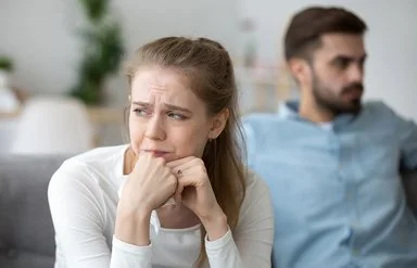 Frau in toxischer Beziehung sitzt traurig auf dem Sofa.