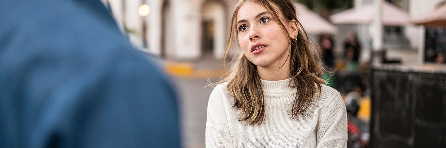 Ein junges Paar streitet sich im Freien. Die Körpersprache und der Gesichtsausdruck der Frau deuten auf Wut oder Frustration hin.