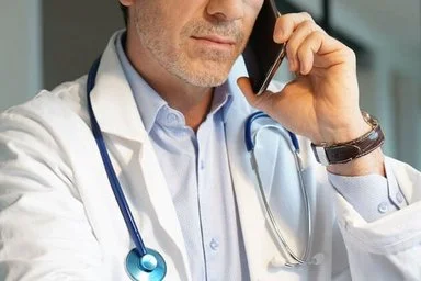 Ein Arzt hält mit der linken Hand ein Smartphone an sein Ohr. Die Fachärzte von AOK-Clarimedis beraten AOK-Versicherte kostenfrei.