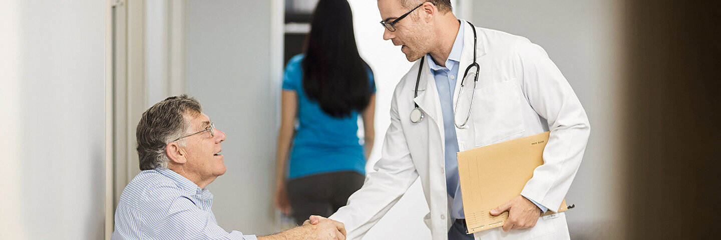 Arzt schüttelt seinem Patienten die Hand, der zur Krebsfrüherkennung in die Praxis kommt.