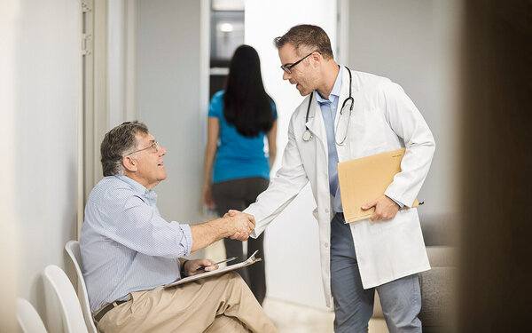 Arzt schüttelt seinem Patienten die Hand, der zur Krebsfrüherkennung in die Praxis kommt.