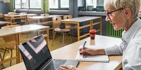 Eine Frau arbeitet mit ihrem Laptop im Klassenzimmer. Sie meldet sich für die Henrietta-Programmeinführung an.