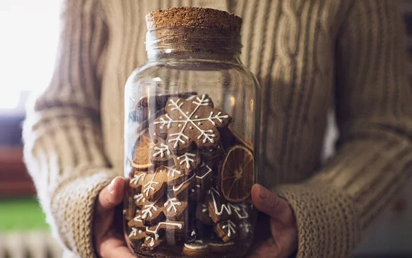 Eine Person verschenkt Lebkuchen in einem wiederverwendbaren Glas.