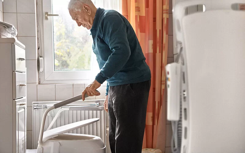 Älterer Mann lebt in einer barrierefreien Wohnung und geht auf die Toilette.