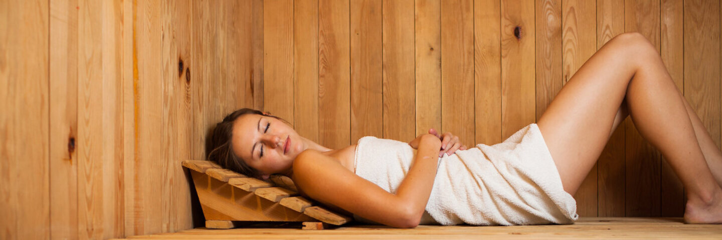 Frau entspannt liegend in der Sauna.