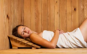 Frau entspannt liegend in der Sauna.