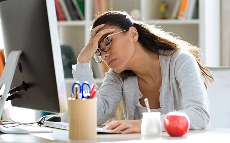 Eine Frau sitzt erschöpft am Arbeitsplatz. Sie hat ein Leistungstief.