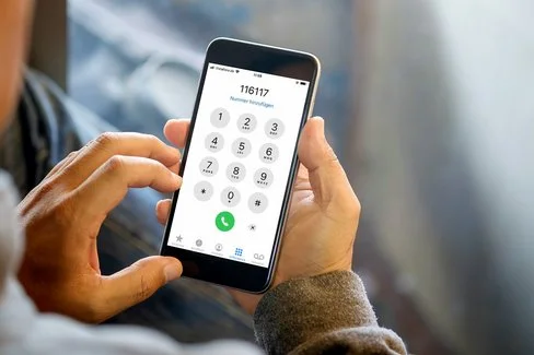 Mann hält Smartphone in der Hand und wählt 116 117.