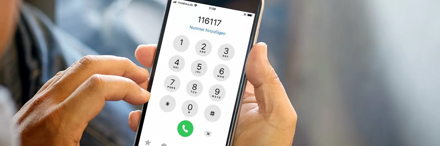 Mann hält Smartphone in der Hand und wählt 116 117.
