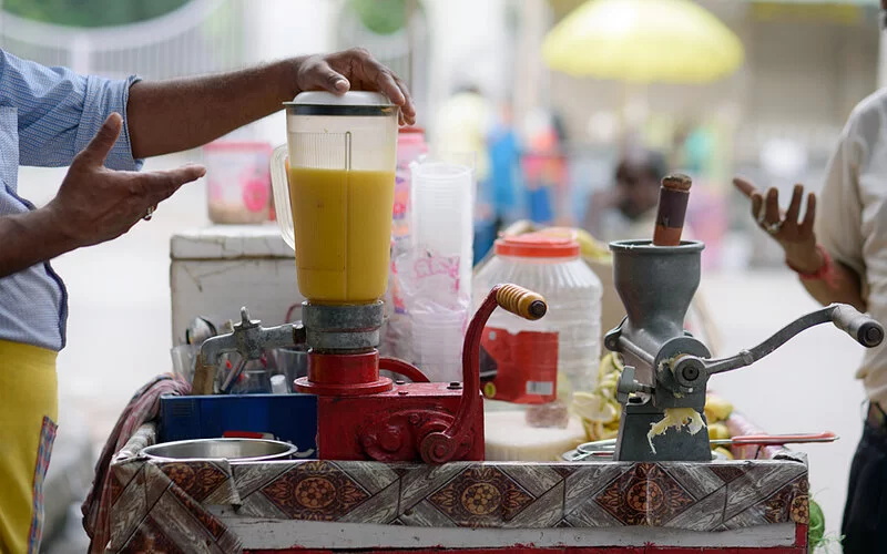 Ein Mann stellt frischen Obstsaft an einem Straßenstand her.