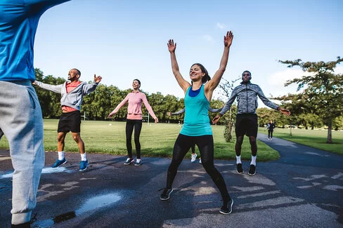 Eine Gruppe Sportler treibt gemeinsam in einem Park Sport.