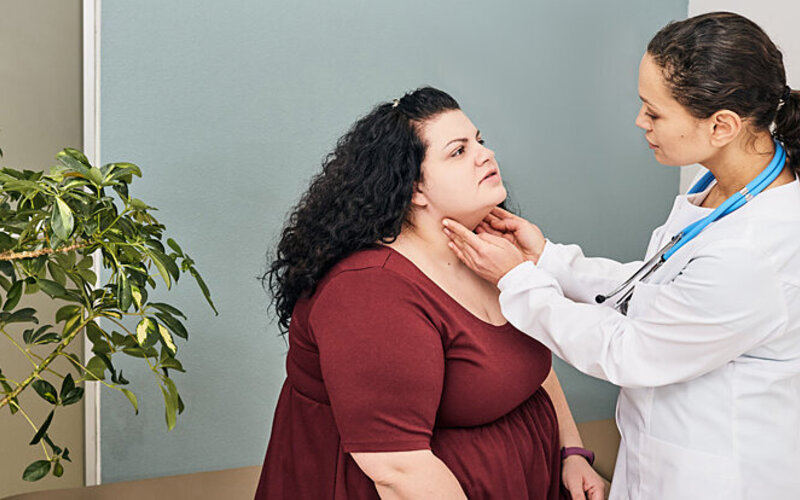 Eine Ärztin untersucht den Hals einer Frau, die an Jodmangel leidet, da dieser zu einer Schilddrüsenunterfunktion führen kann.