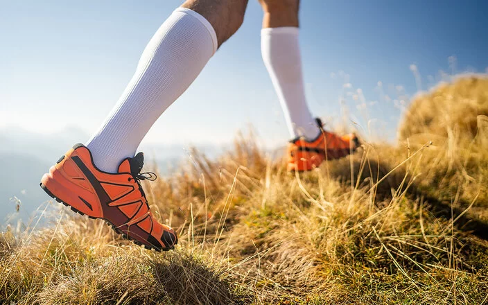 Detailaufnahme der Beine eines Läufers mit Laufschuhen und Kompressionsstrümpfen.
