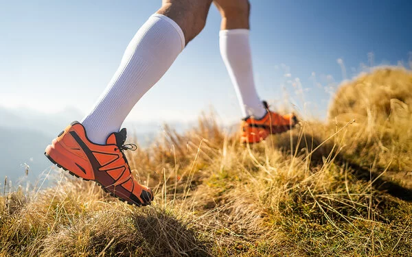 Detailaufnahme der Beine eines Läufers mit Laufschuhen und Kompressionsstrümpfen.