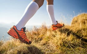 Detailaufnahme der Beine eines Läufers mit Laufschuhen und Kompressionsstrümpfen.