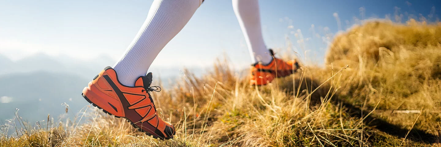 Detailaufnahme der Beine eines Läufers mit Laufschuhen und Kompressionsstrümpfen.
