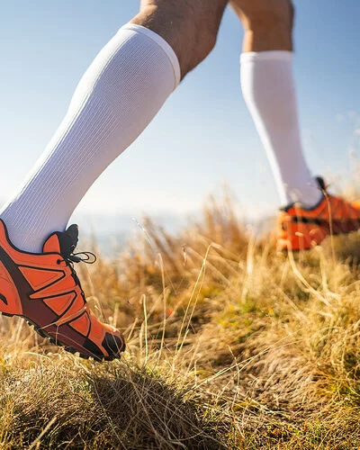 Detailaufnahme der Beine eines Läufers mit Laufschuhen und Kompressionsstrümpfen.
