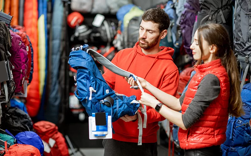 Ein Mann und eine Frau betrachten in einem Outdoor-Geschäft einen Wanderrucksack.