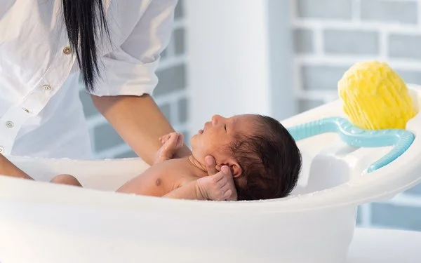 Ein Baby wird in einer Babybadewanne gebadet.