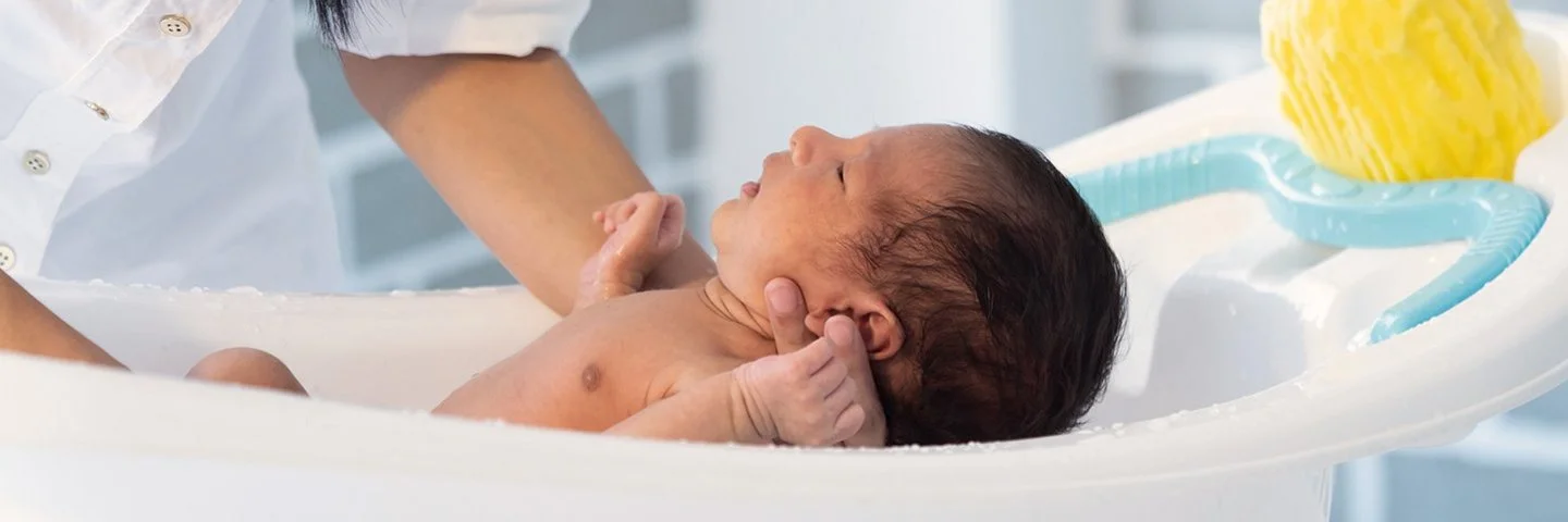 Ein Baby wird in einer Babybadewanne gebadet.