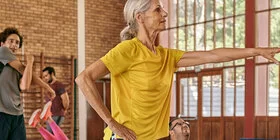 Mehrere Personen in Sportkleidung machen Übungen in einer Sporthalle. Die AOK unterstützt Sie in Sachen Bewegung. 