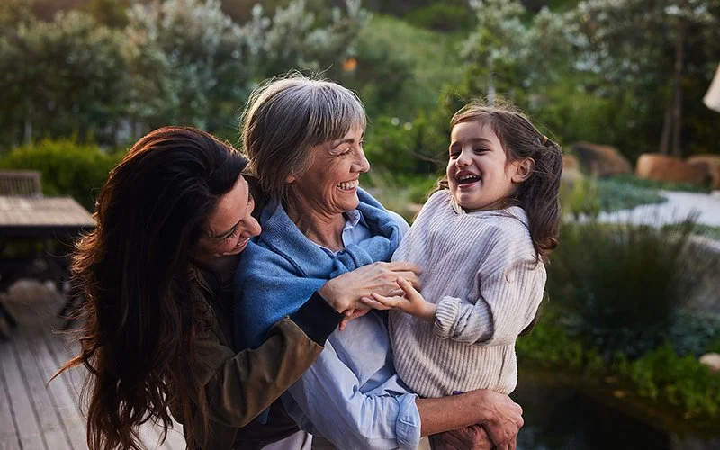 Drei Generation: Ein Kleines Mädchen, seine Mutter und die Großmutter lachen zusammen im Garten.