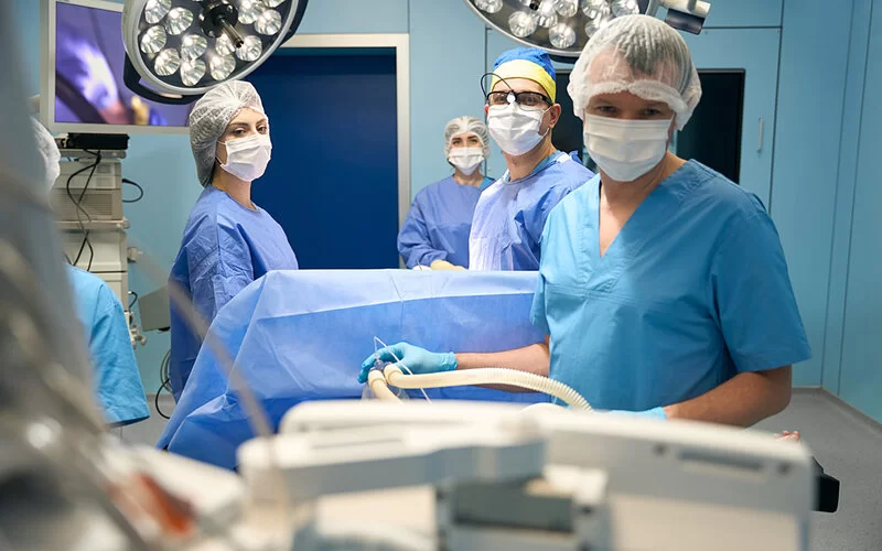 Ärzte und Ärztinnen in einem Operationssaal kontrollieren die Werte eines Patienten oder einer Patientin.