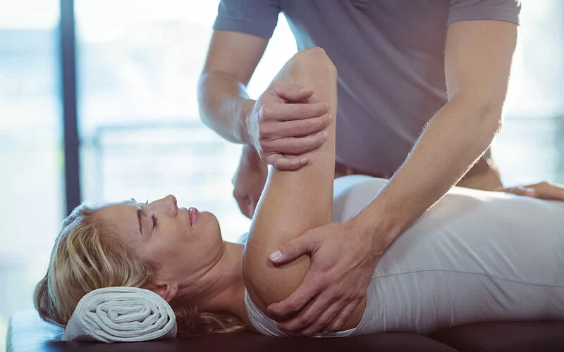 Eine Frau ist beim Physiotherapeuten, um ihre Schulter behandeln zu lassen.