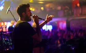 Ein Sänger mit Mikro in der Hand singt in Richtung des Publikums.