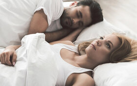 Ein Paar liegt im Bett, doch die Frau kann nicht einschlafen, leidet vielleicht an Schlaflosigkeit.