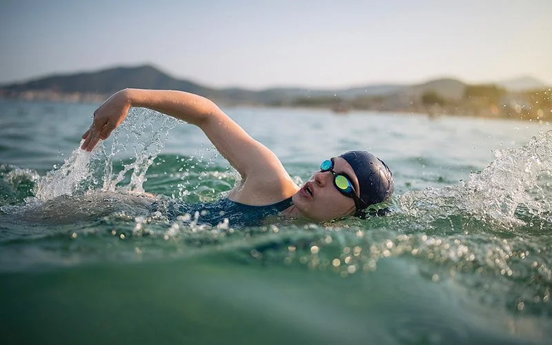 Eine Frau schwimmt sportlich im Freiwasser.