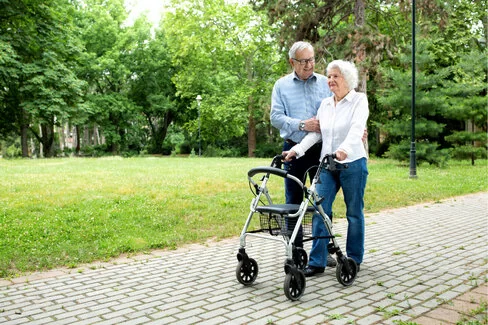 Eine Frau nutzt als Unterstützung beim Gehen einen Rollator. Gehhilfen erleichtern den Alltag von Patienten.