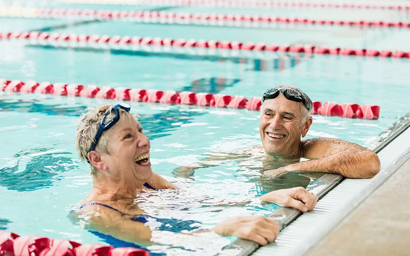 Älteres Ehepaar treibt Sport in der Schwimmhalle.