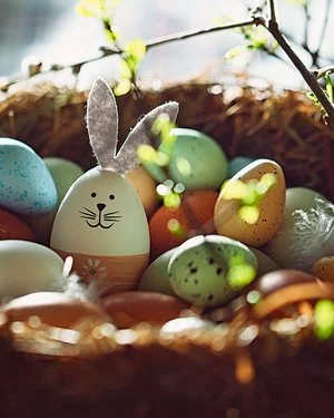 In einem Osternest aus Stroh und Zweigen liegen selbstbemalte und verzierte Ostereier..