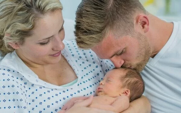 Junge Mutter und Vater mit Neugeborenem im Arm