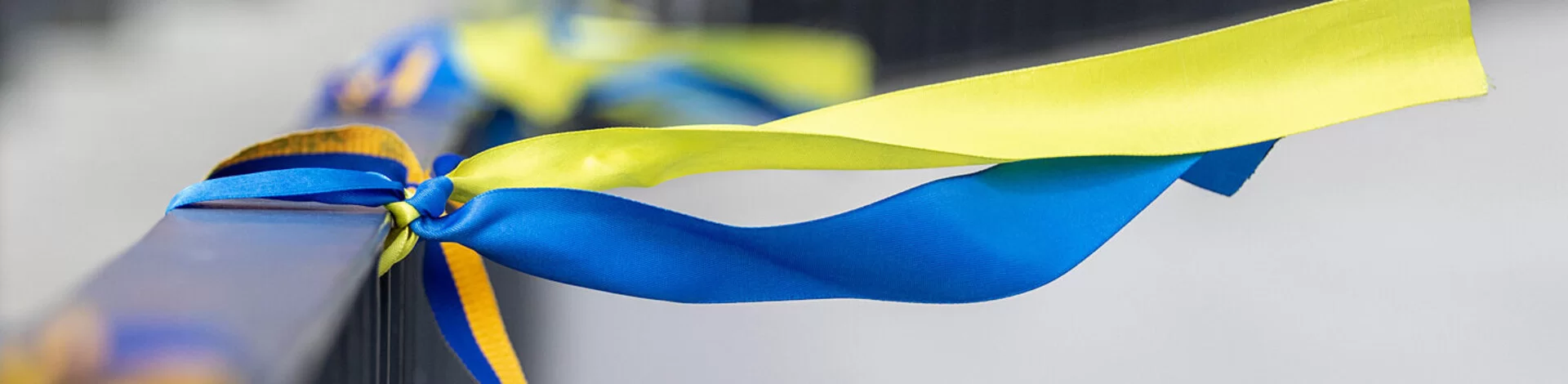 Bänder in den Farben der Nationalflagge der Ukraine sind an ein Geländer einer Brücke gebunden.