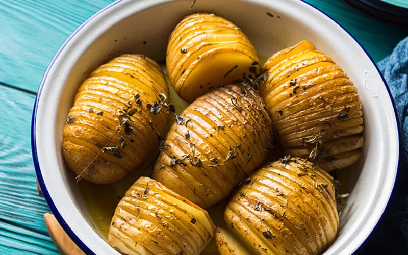 In einer Schale liegen mehrere fein eingeschnittene Kartoffeln mit Schale.