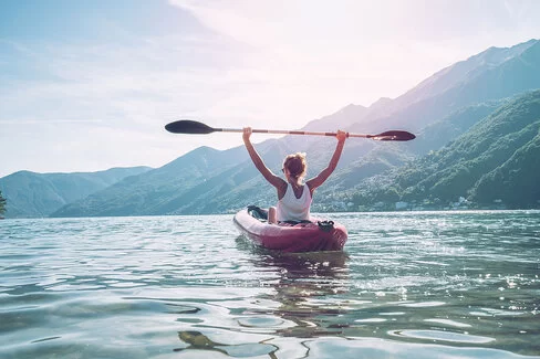 Eine junge Frau beim Kanufahren auf einem Bergsee.