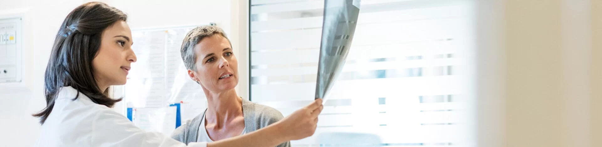 Eine Ärztin erklärt ihrer Patientin anhand von Röntgenbildern den aktuellen Befund. Gemeinsam besprechen sie das weitere Vorgehen.