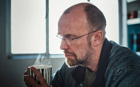 Ein Mann um die 50 mit Midlife-Crisis trinkt resigniert einen Kaffee.