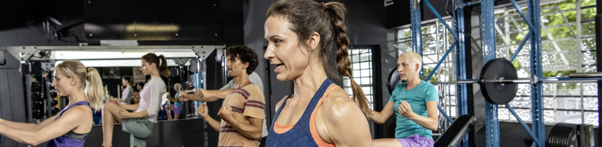 Sportliche Frauen und Männer trainieren in einem Studio.