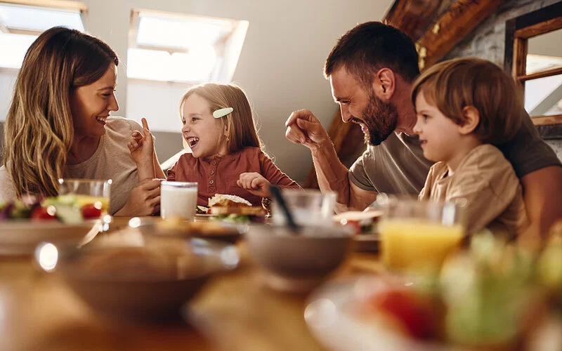 Eine vierköpfige Familie sitzt gemeinsam mit an Diabetes erkranktem Kind am Frühstückstisch.