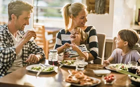 Eine Familie mit zwei Kindern isst zusammen und hat Spaß.