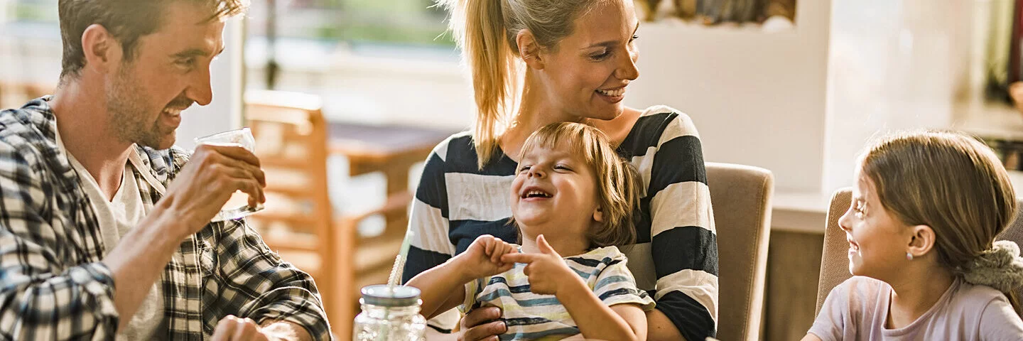 Eine Familie mit zwei Kindern isst zusammen und hat Spaß.