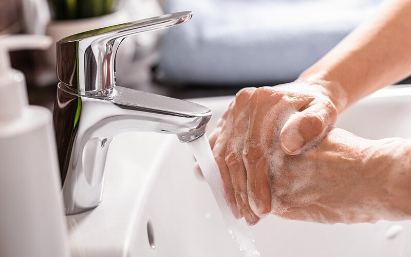 Ein paar männliche Hände werden mit reichlich Seife über dem Waschbecken gewaschen.