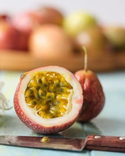 Eine Passionsfrucht liegt durchgeschnitten auf einem Tisch. Das Fruchtfleisch und die Kerne sind gut zu erkennen.