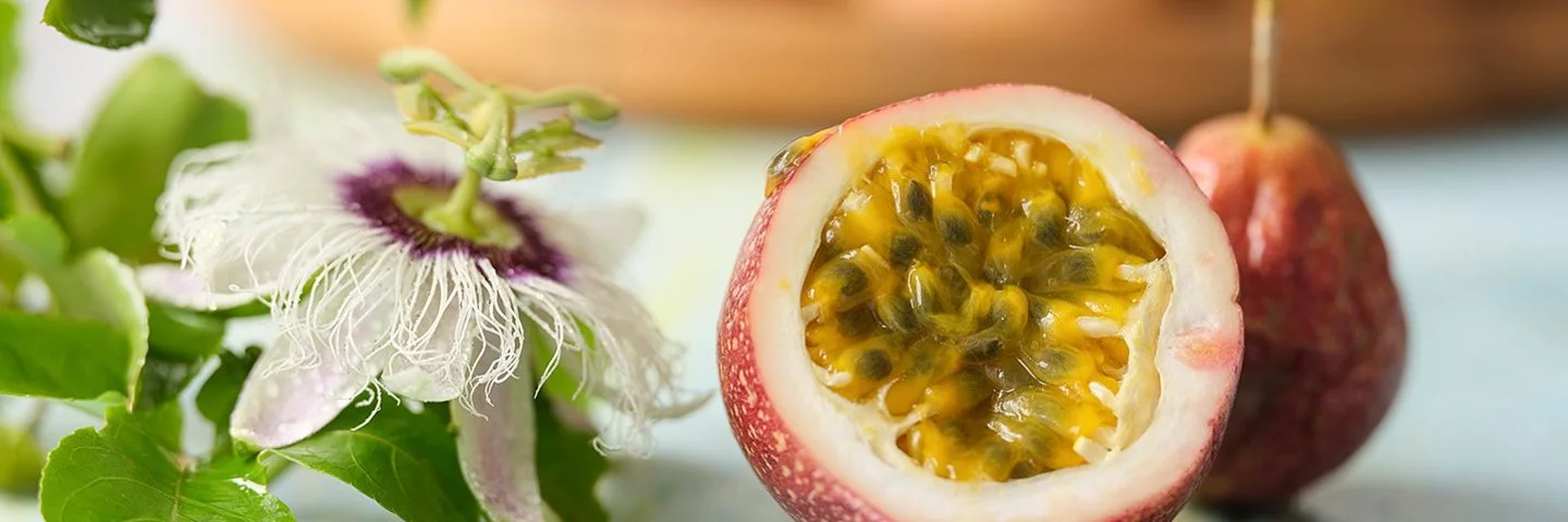 Eine Passionsfrucht liegt durchgeschnitten auf einem Tisch. Das Fruchtfleisch und die Kerne sind gut zu erkennen.